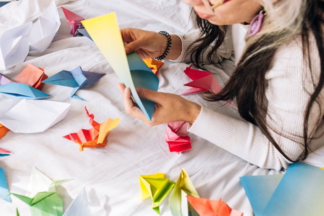 Learning by doing is facilitated by meta learning strategies afterward. Photo of person making origami shapes.