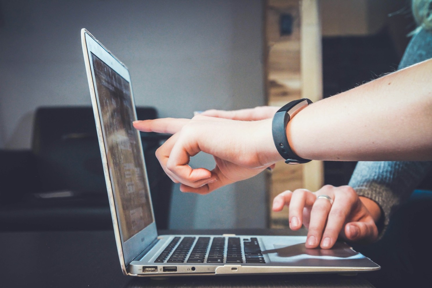 two people with hand pointed to computer screen