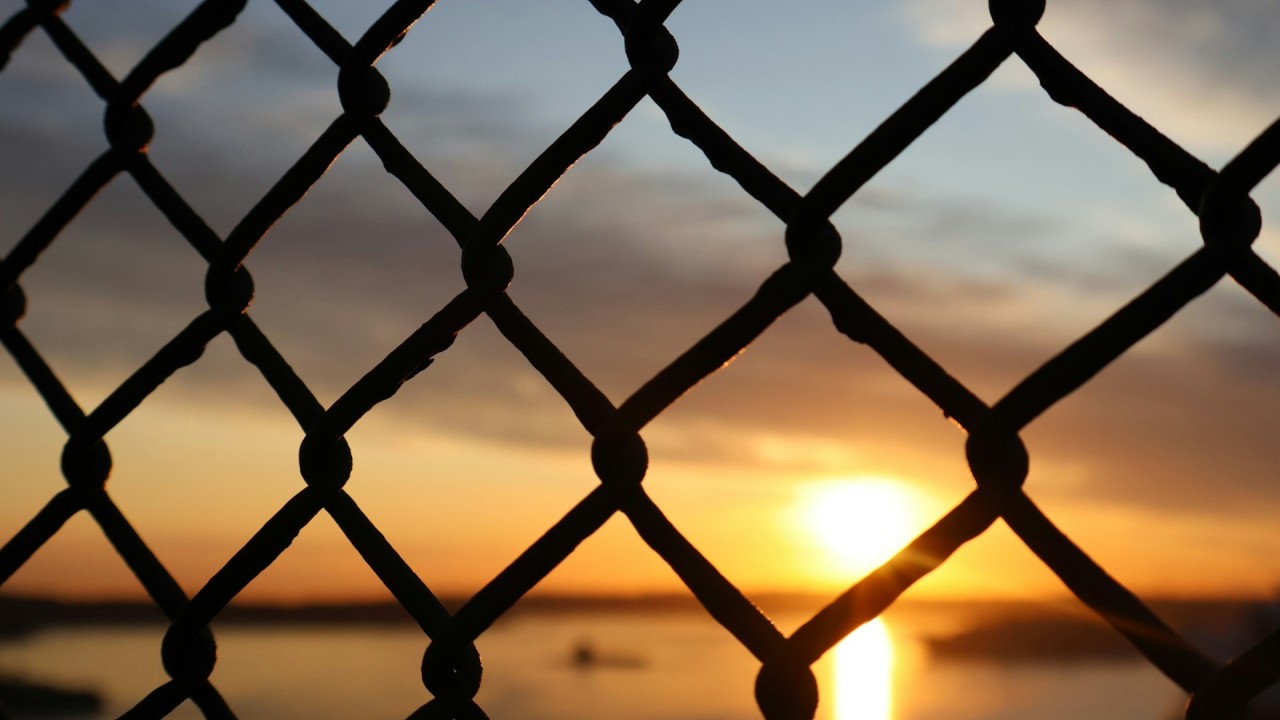 Photo of sunrise through fence. Creating healthy boundaries is about building resilience and agency.