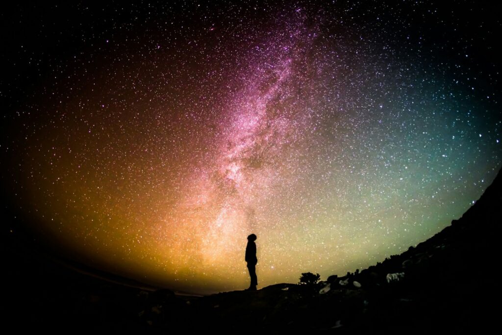 Being in nature is a strategy to reduce digital overwhelm. Photo of person at night staring at stars.